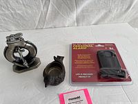 All three items: nautical metal lighter, cast-iron bird holder, sealed personal alarm