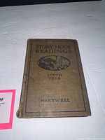 Front cover of brown cloth hardcover showing title, illustration, wear at corners