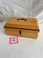 Closed jewelry chest showing wood finish, handle and lock with key inserted