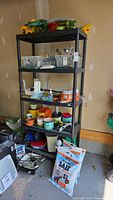 Front view of 4-tier black plastic shelving unit with miscellaneous contents (contents excluded)