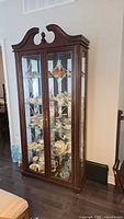 Front view of dark wood Bühler curio cabinet with double glass doors and interior shelves