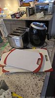 Air fryer, toaster, three cutting boards on countertop