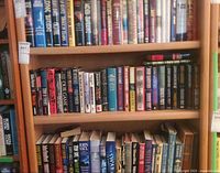 Three shelves filled with assorted thriller and sci-fi hardcovers & paperbacks