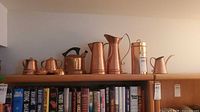 All eight Gregorian hammered copper pieces displayed on shelf