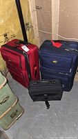 Red and navy large upright suitcases with black rolling carry-on in front