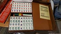 Open brown carrying case showing two trays of Mahjong tiles, coloured scoring sticks and white spacers