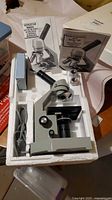 Microscope in styrofoam insert with manuals, eyepiece and cord visible