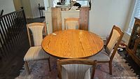 Round oak dining table with four chairs visible