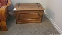 Front view of closed wooden blanket chest beside chair