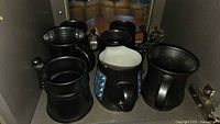 Group of seven stoneware tankards inside cabinet