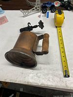 Side view of brass blow torch beside tape measure showing overall size and wooden handle