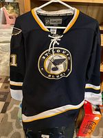 Front view of navy St Louis Blues jersey showing crest and sleeve number