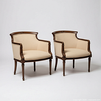 Front three-quarter view of both bergère armchairs showing upholstery and carved walnut frames