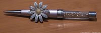 Pen and brooch side by side on tabletop