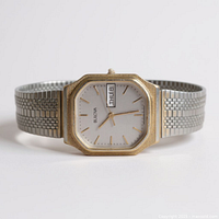 Front view showing gold-tone octagonal bezel, silver dial, day-date window, and mesh bracelet