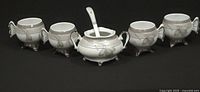 Entire set: sugar bowl with lid and spoon, four footed bowls