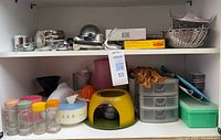 Cabinet shelves displaying mixed kitchen gadgets, spice jars, plastic items, boxed pieces