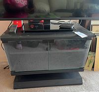 Front view of black TV stand with glass doors closed