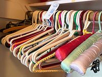 Front view showing mixed plastic, padded, metal, and wood hangers on closet rod