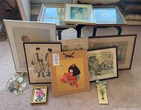 Group shot showing majority of framed pieces, unframed prints stacked at back, stained glass plaque and pressed botanical plaque in foreground