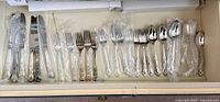 Drawer view showing entire assortment of knives, forks, spoons, some in plastic