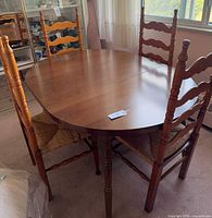 Oval wooden dining table with four ladder-back chairs around it