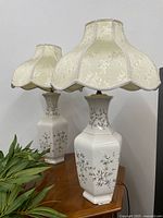 Both ceramic lamps on wooden surface showing bases and shades