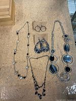 Overview of all jewelry items laid out: three necklaces, two pairs earrings