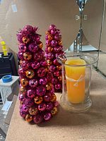 Two gem-covered cone trees and glass hurricane with candle on tabletop
