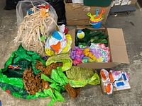 Overall lot with raffia skirts, deflated inflatables, leis, leaves, boxed beach balls, bucket