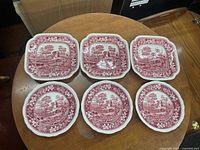 Six red transferware plates, three square and three round, displayed top view