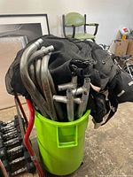 Curved metal frame tubes, T-connectors, net and mat inside green trash can