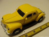 Front/side view of yellow Tootsietoy 1940 Ford Coupe with ruler for scale