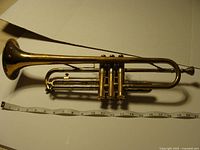 Full view of trumpet beside measuring tape showing approximately 19 inch length