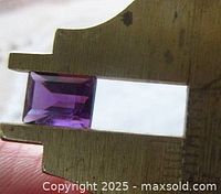 Amethyst stone held in caliper showing dimensions and rectangular shape