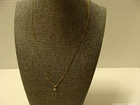 Full view of 18K gold necklace on display bust showing chain length and style