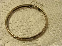 Full view of oval sterling bangle showing hinge and safety chain