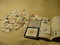 Wide view of loose stamps spread out beside open stamp album