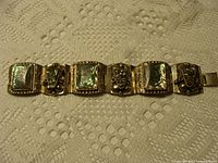Full view of bracelet showing five alternating abalone and mask panels