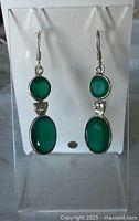 Front view of both sterling silver earrings showing round and oval green gemstones