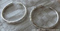 Both hoop earrings lying flat showing faceted texture