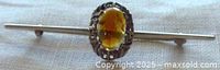 Front view showing bar brooch, scrolled frame and amber stone