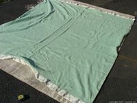 Full view of mint green merino wool blanket laid flat outdoors