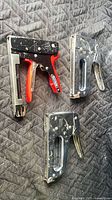 Group shot of three staple guns on quilted surface