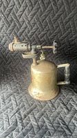 Left-side view of brass-plated blow torch showing handle, tank, burner and flame tube