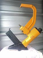 Full view of yellow Bostitch pneumatic flooring stapler showing handle, body, magazine and air fitting