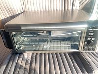 Front view of Ninja FT102 air fry oven showing stainless body, glass door and accessories inside