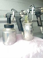 Two Powerhouse siphon-feed spray guns side by side showing overall form and cups