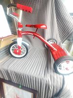 Full view of red Radio Flyer Classic tricycle on display surface