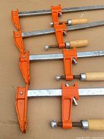 Four bar clamps laid out showing heads and handles